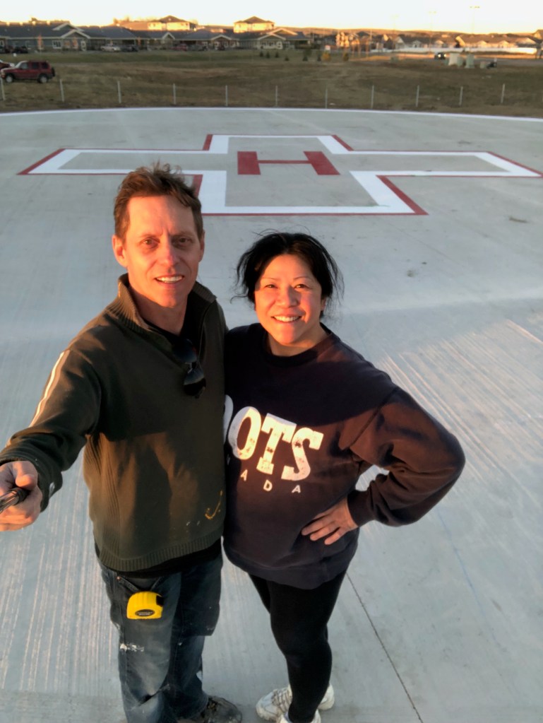 Helicopter landing pad painted in red and white according to regulations. Road painter crew in front of road marking.
